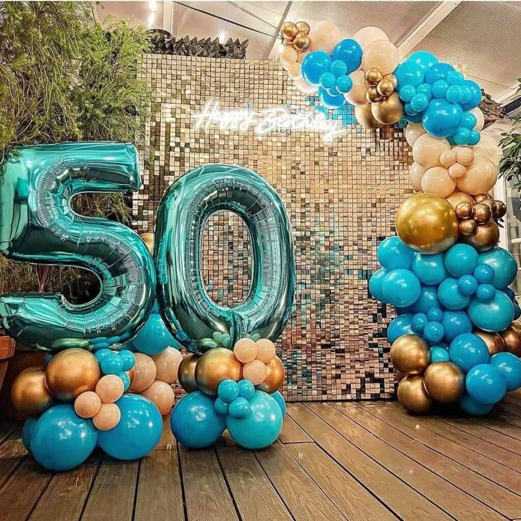 decoración 50 cumpleaños tábatha decora tu fiesta con shimmer wall dorado y arco de globos dorados y turquesa con globos en forma de números 50